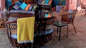 A cozy outdoor seating area with wicker furniture, a wooden table, and a yellow towel.