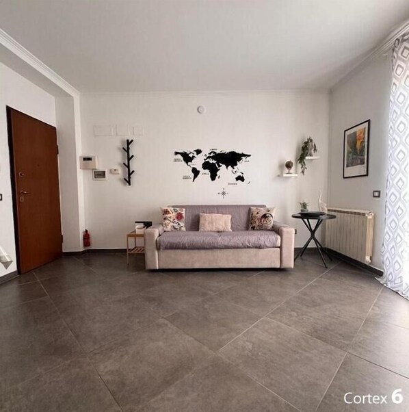 Una sala de estar moderna con un sofá gris, una decoración de mapa mundial en la pared y una mesita auxiliar pequeña.