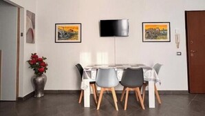 Ein Essbereich mit Tisch und Stühlen, einem flachbildfernseher an der Wand und gerahmten Bildern.