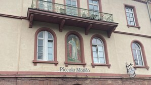 A building with a sign reading "Piccolo Mondo." It features a balcony with ornate railings, multiple windows, and a door with a unique pattern. - Charming studio with AC, balcony and view of the Castle - Walk to Everything. (Heidelberg)