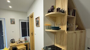 Een compacte keuken met een ingebouwde kookplaat, houten planken en een eethoek met een bank.