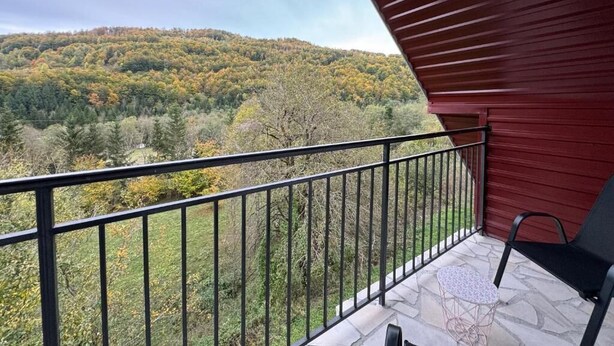 Een balkon met uitzicht op een bebost heuvellandschap.