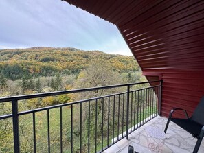 Een balkon met uitzicht op een bebost heuvellandschap.