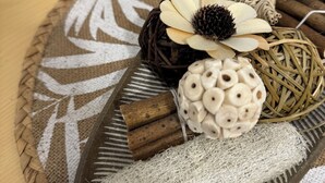 Een dienblad met decoratieve items, waaronder een fles wijn, een geweven mand en verschillende natuurlijke elementen zoals takken en een bloem.