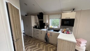 A modern kitchen with a herringbone floor pattern, a built-in oven, a sink, and a microwave.