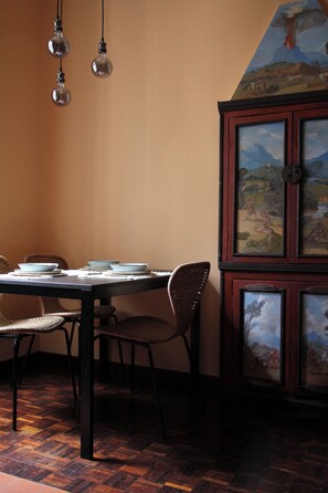 Zona pranzo con tavolo in legno, sedie e lampadari.