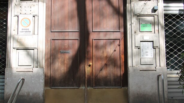 Une porte en bois à deux battants, dotée d’une poignée en métal, un panneau indiquant qu’il est interdit de se garer, et un panneau vert au-dessus de la porte.