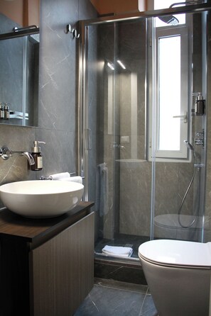 Un bagno moderno con doccia vetrata, lavandino bianco e servizi igienici.