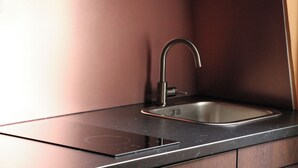 Une cuisine moderne dotée d’un élégant plan de travail noir, d’un évier en acier inoxydable et d’un seul robinet.