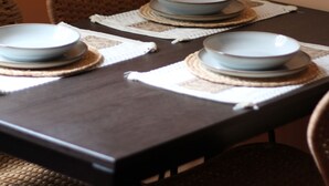 Une table à manger dressée avec des assiettes et des bols, entourée de chaises en osier.