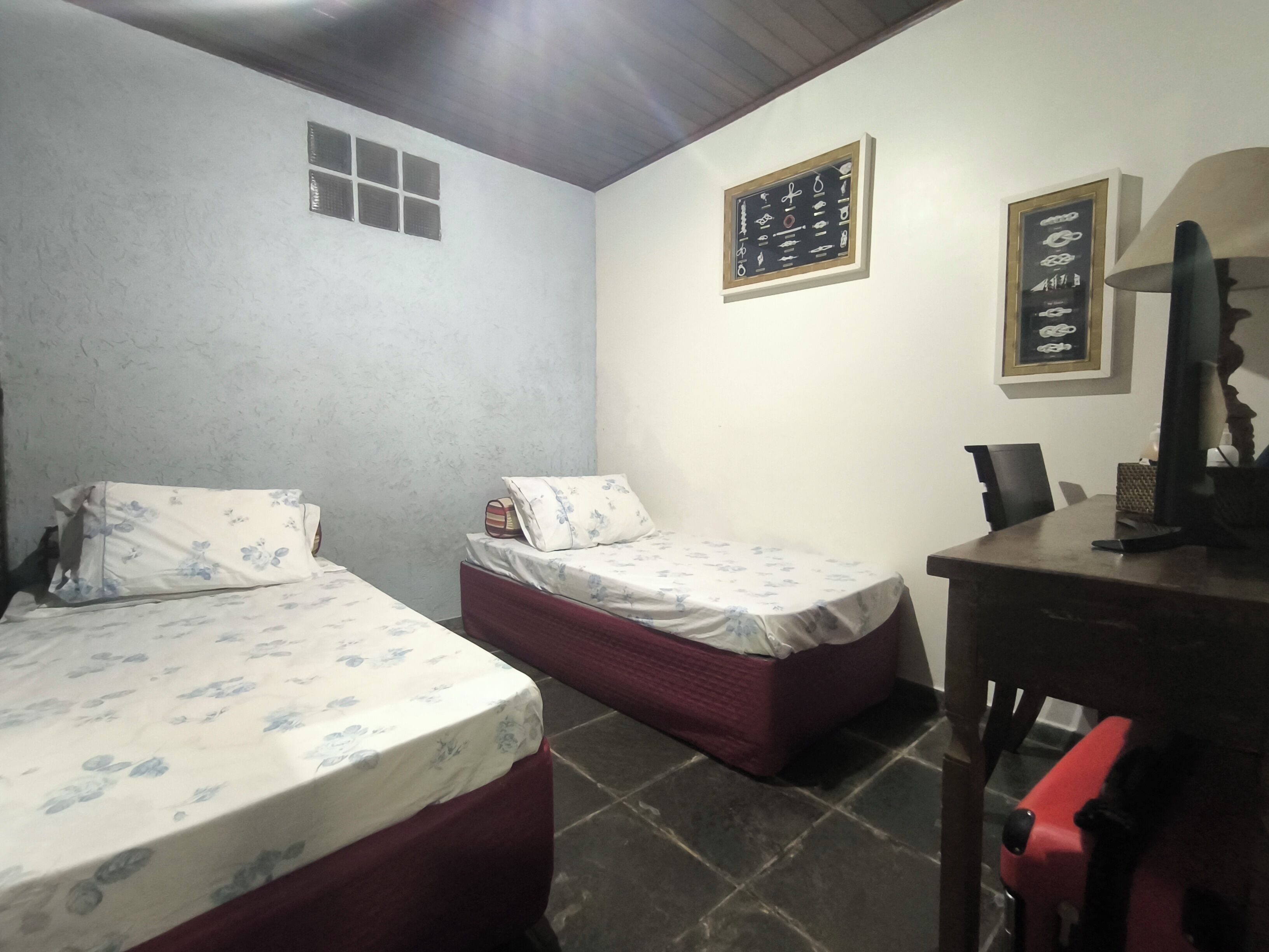 Een kleine, schemerige kamer met twee bedden, een bureau en een stoel.