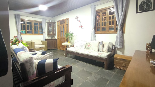 A cozy living room with a sofa, a wooden bench, a small table, and a cabinet. - Beach retreat (São Sebastião)