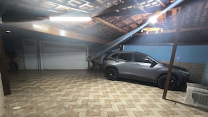 A garage with a patterned floor, a parked SUV, and a blue wall. - Beach retreat (São Sebastião)