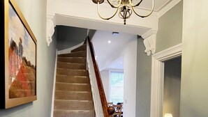 Una escalera con alfombra estampada que conduce a un comedor.