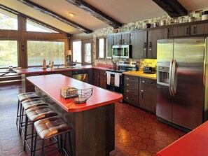 A modern kitchen with a central island, stainless steel appliances, and a large window providing natural light.