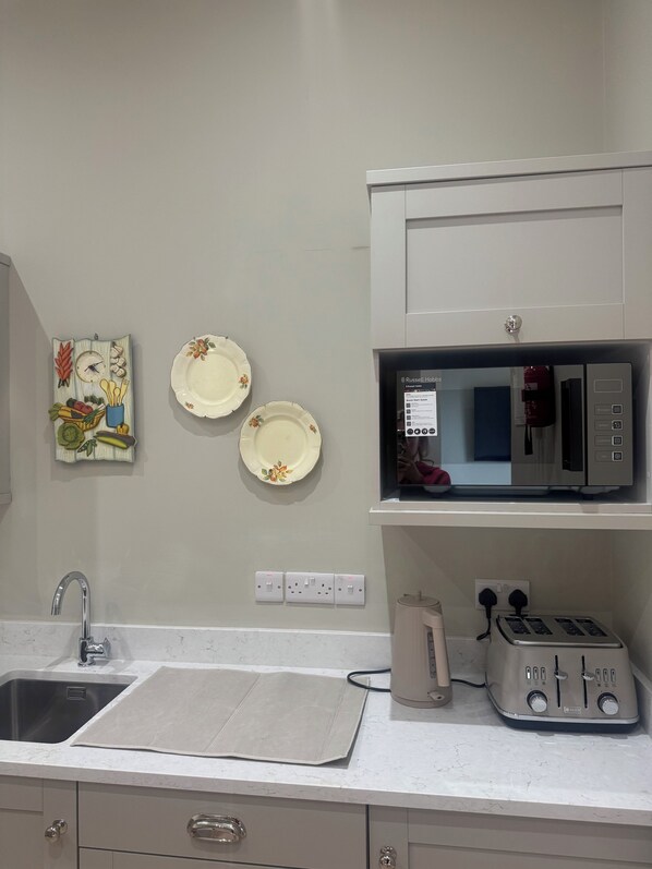 A kitchen with a microwave, toaster, and a sink.