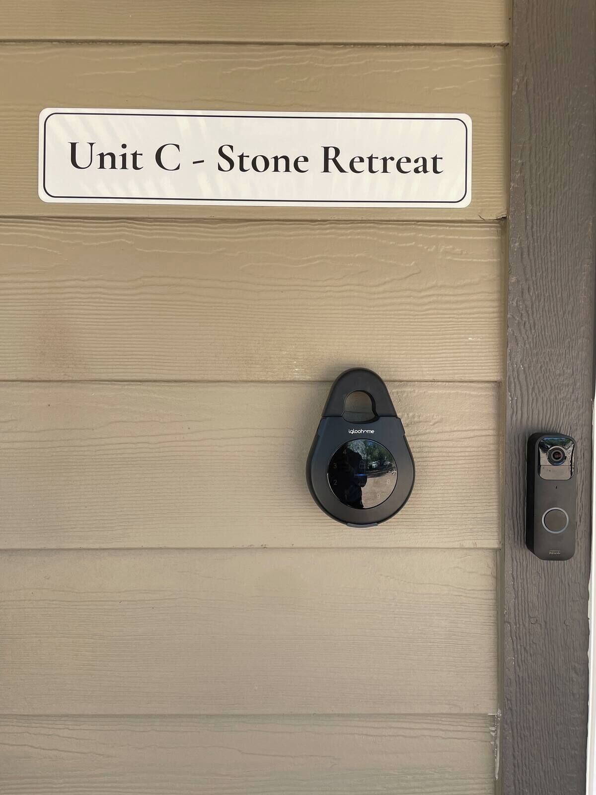 A door with a sign reading 'Unit C - Stone Retreat' and a black security device on the door.