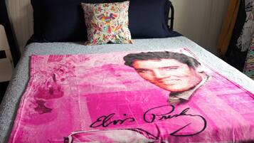 A bed with a colorful pillow and a blanket featuring a celebrity's portrait and signature.