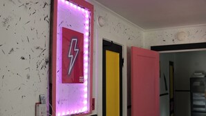 Un mur orné d’un panneau néon sur lequel on peut lire « Heart Break Hotel » et une porte avec un panneau jaune.