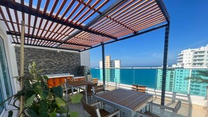 A covered outdoor dining area with a stone wall and a view of the ocean. - Style and comfort by the Caribbean (Gaira)