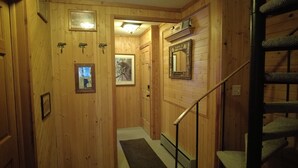 A wooden hallway with a staircase, framed pictures, and a mirror on the wall.
