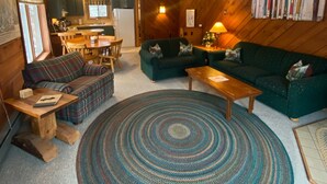 A cozy living room with a green sofa, a wooden coffee table, and a patterned rug. - Powdery Peak Ski Chalet- Where Mountain Memories Begin (Bessemer)