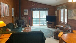 A cozy living room with a fireplace, a television, and a dining area. - Powdery Peak Ski Chalet- Where Mountain Memories Begin (Bessemer)