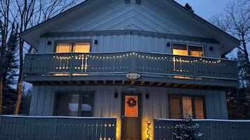 Een twee verdiepingen tellend huis met een balkon, een welkomswiel en een bord dat het een skigebied aangeeft.