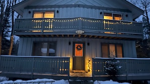 A two-story house with a balcony, a welcome wreath, and a sign indicating it is a ski resort. - Powdery Peak Ski Chalet- Where Mountain Memories Begin (Bessemer)