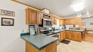 A kitchen with wooden cabinets, a microwave, stove, and a sink.