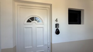 En vit dörr med ett litet fönster ovanför, en väggmonterad intercom och en skylt med siffran ’4’.