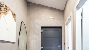 A hallway with a modern design, featuring a wooden herringbone floor, a dark door, and a light-colored wall with a piece of abstract art. - A2 luxury apartment near beach with big terrace and the sea view (Kaštel Gomilica)