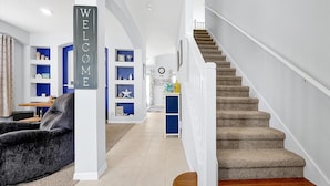A modern interior with a staircase, a 'WELCOME' sign, and a blue accent wall. - Emerald Island Resort 6 Bed Pool & Spa-10min to Disney! (Kissimmee)