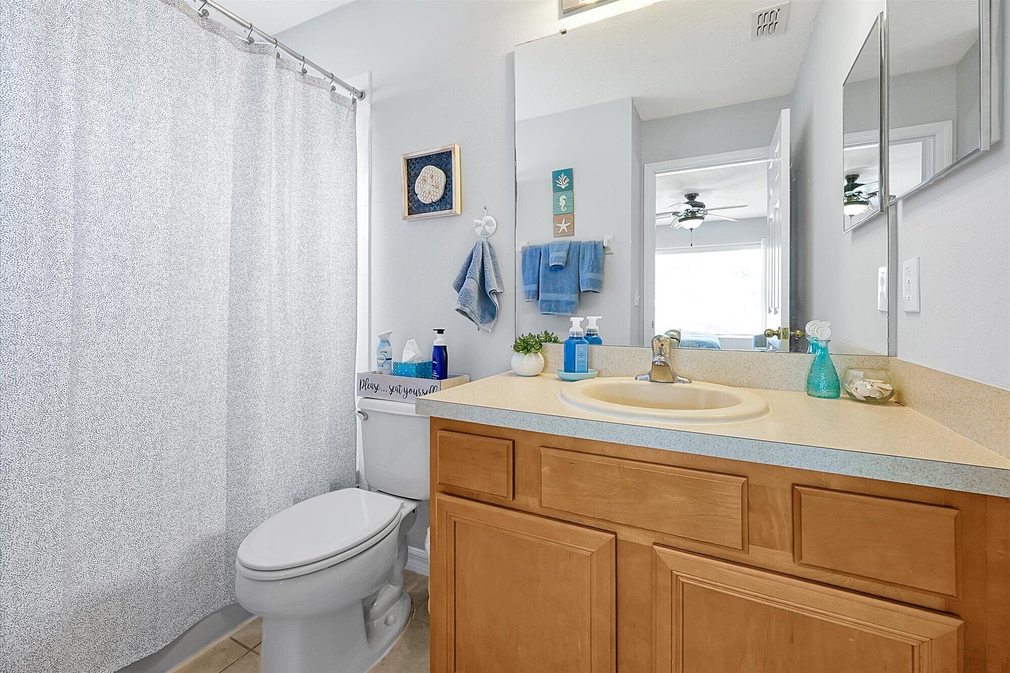 Une salle de bain avec un rideau de douche, des toilettes, un lavabo et un meuble-lavabo.