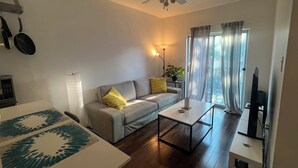 Un salon avec un canapé, une table basse, un téléviseur et un ventilateur de plafond.