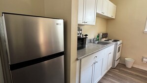 Una cocina moderna con armarios blancos, un refrigerador de acero inoxidable, un microondas y una estufa.