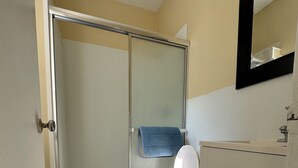 Un baño con inodoro, cabina de ducha y lavamanos.