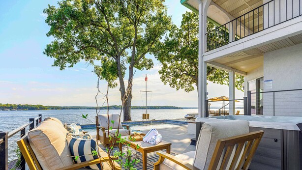 A deck with outdoor seating, a hot tub, and a view of a lake. - Panoramic Paradise - Lakefront Home for 15 (Rocky Mount)
