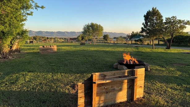 Un espacio al aire libre con césped, un banco de madera y un hogar para fuego.