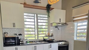 A modern kitchen with white cabinets, a black countertop, a stove, and a large window with a view of greenery.