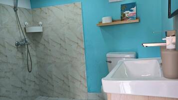 A bathroom with a shower, toilet, sink, and marble flooring.