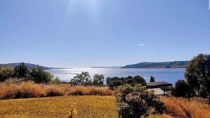 A coastal landscape with a clear sky, a body of water, and a small building in the foreground. - Double room in a family home (Dalcahue)