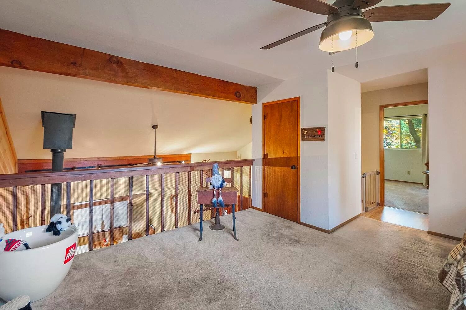 Une pièce spacieuse avec un plafond haut, un ventilateur de plafond, une porte en bois et une vue sur l’extérieur.