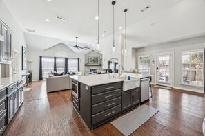 A spacious kitchen with a large island, dark cabinetry, and pendant lighting.