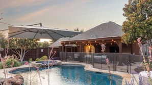A backyard with a swimming pool, patio furniture, and a covered seating area. - Luxury 4BR Smart Home w/ Pool, Spa, Media Room & Pet-Friendly Yard (Frisco)
