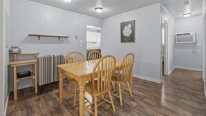 A dining area with a wooden table and chairs, a radiator, a shelf, and a framed picture on the wall. - 10mins to Air force base|Smart TV|Self Check-In (Mountain Home)