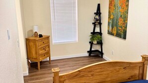 Une chambre à coucher avec un lit en bois, une commode, un globe terrestre et un tableau.