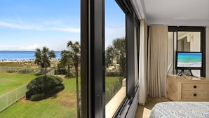 Une chambre d’hôtel avec une grande fenêtre, un lit, une télévision et vue sur la plage.