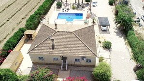 A villa with a tiled roof, a swimming pool, and a garden with palm trees. - Mediterranean villa with private pool 20 minutes from the beaches of La Marina (Catral)