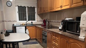 A kitchen with wooden cabinets, a microwave, a coffee maker, a sink, and a dining table with chairs. - Mediterranean villa with private pool 20 minutes from the beaches of La Marina (Catral)